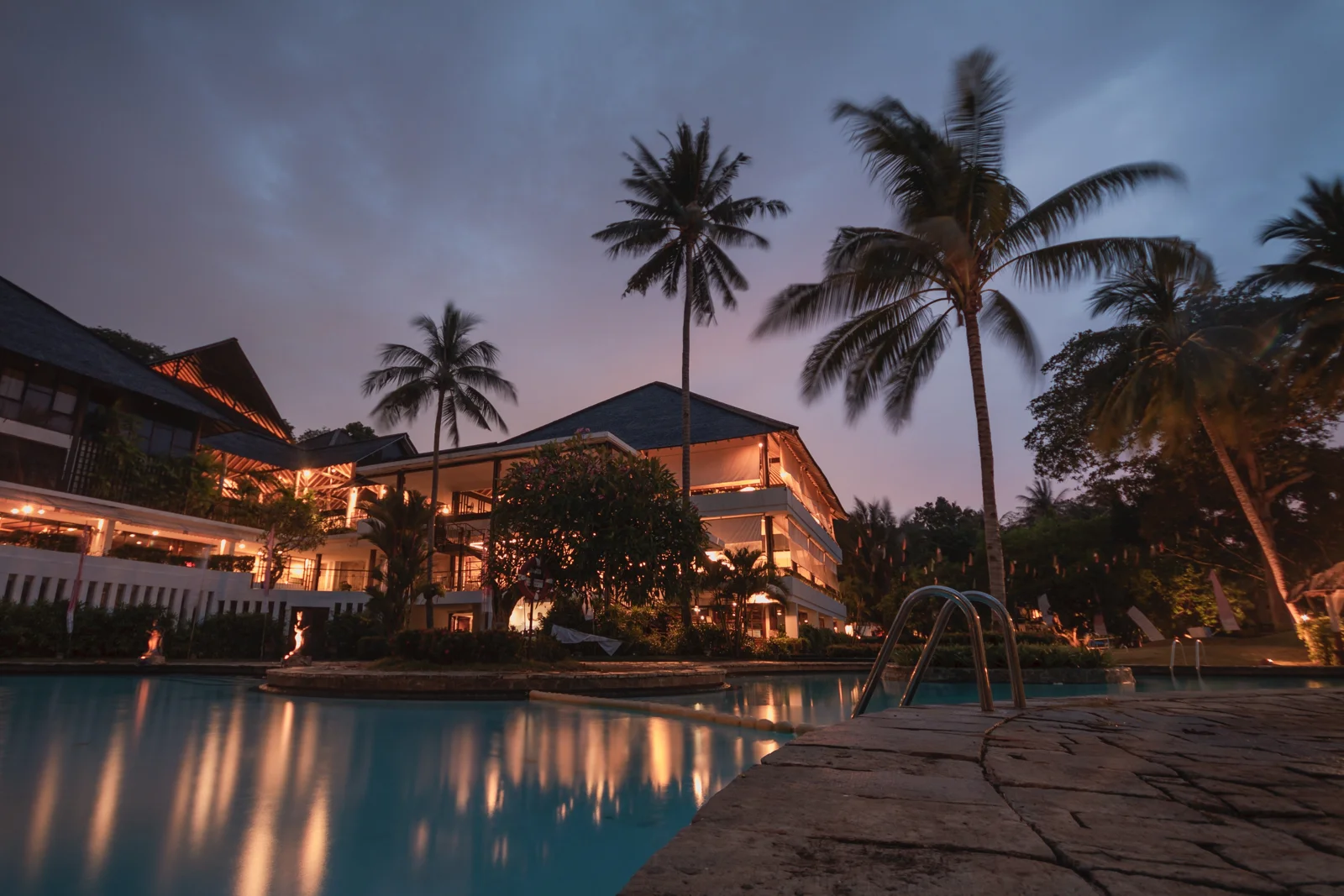 Hotel swimming pool and palm trees at dusk