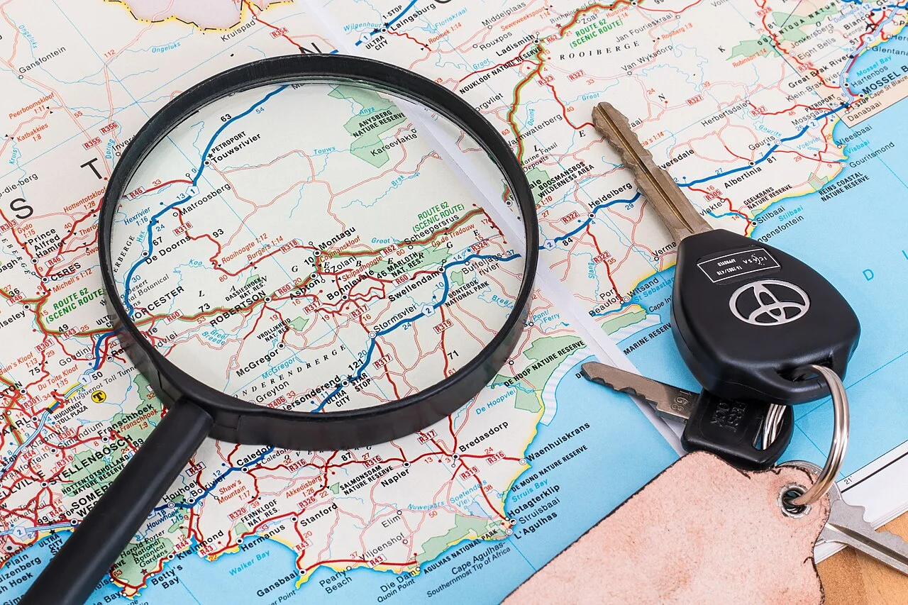 Road map with a magnifying glass and car keys for planning a trip